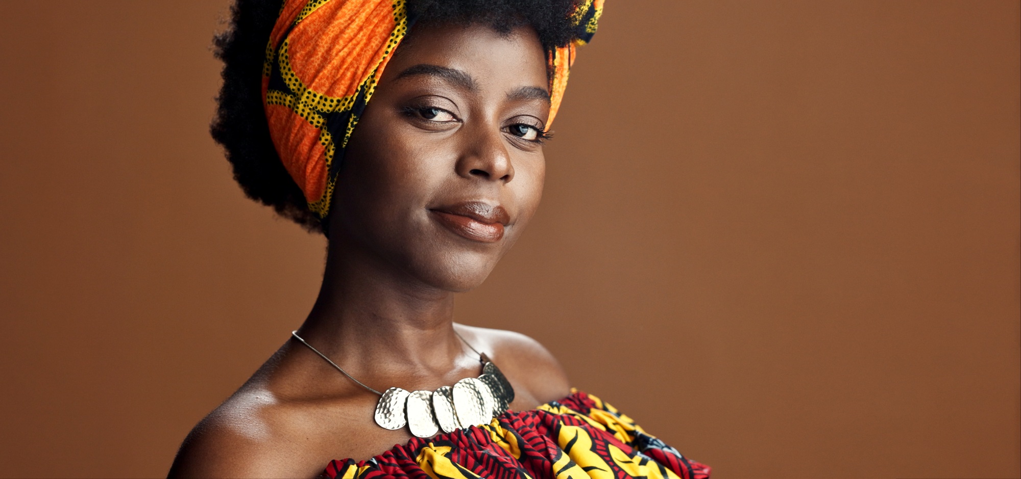 Culture, African fashion or face of black woman in studio on a brown background for trendy style. U